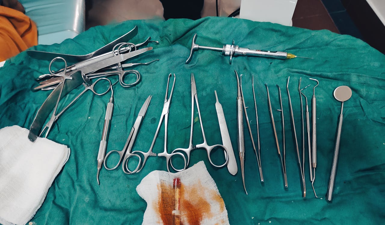 Close-up view of surgical tools arranged on green medical drapes in a clinical setting.