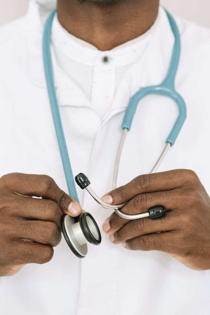 A close-up of a doctor holding a stethoscope wearing a white coat.