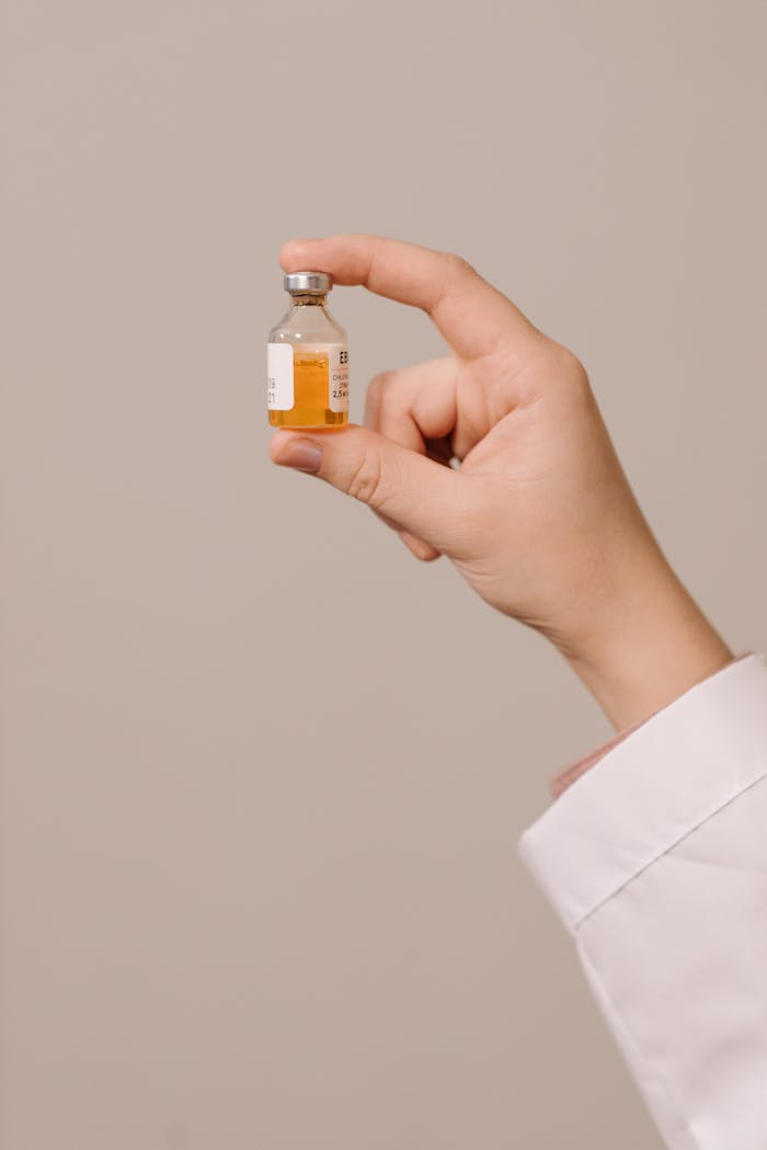 Detailed image of a hand holding a medicinal vial, essential for vaccinations and pharmacology.