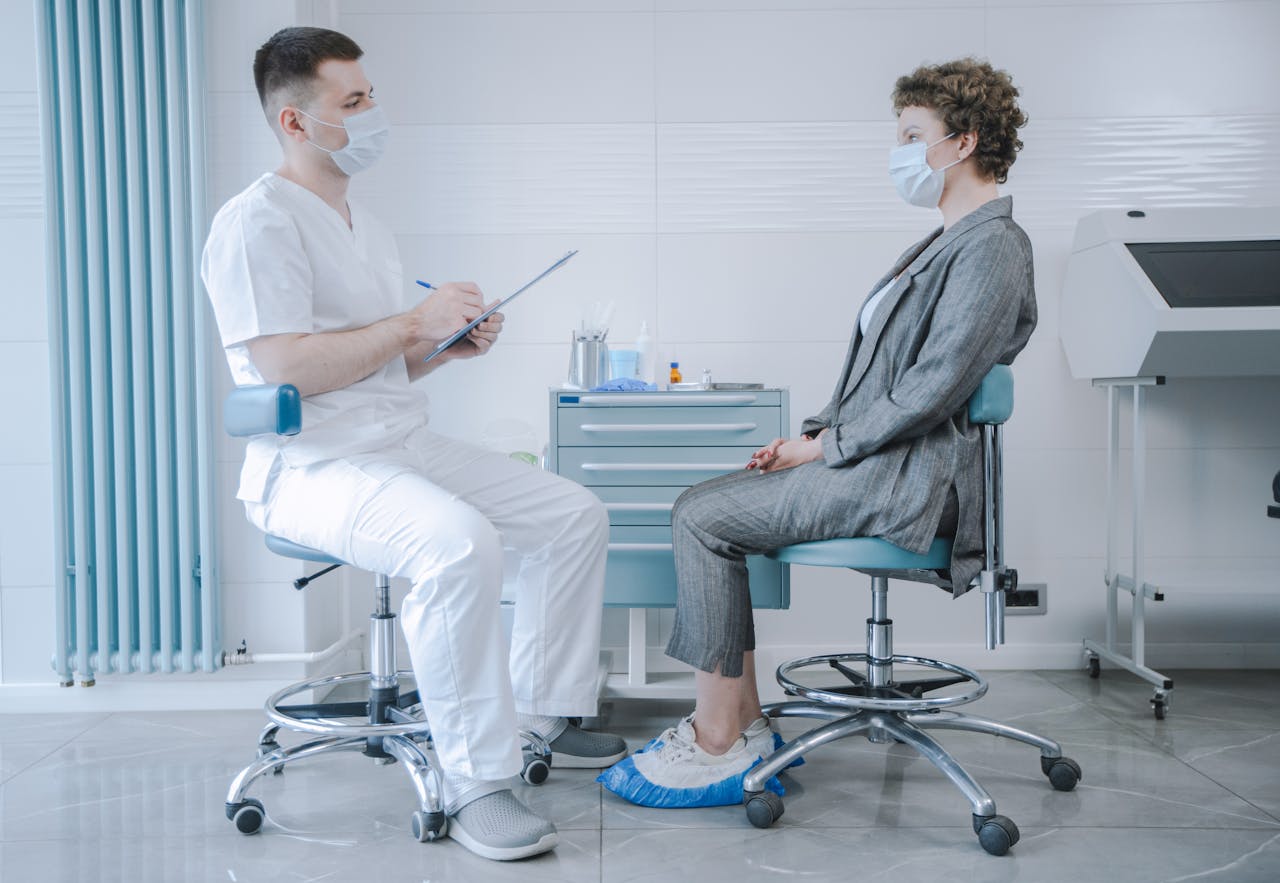 Doctor and patient wearing masks during a consultation in a clinical setting.